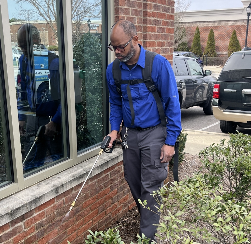 serving image man spraying chemicals outside of home for pest control